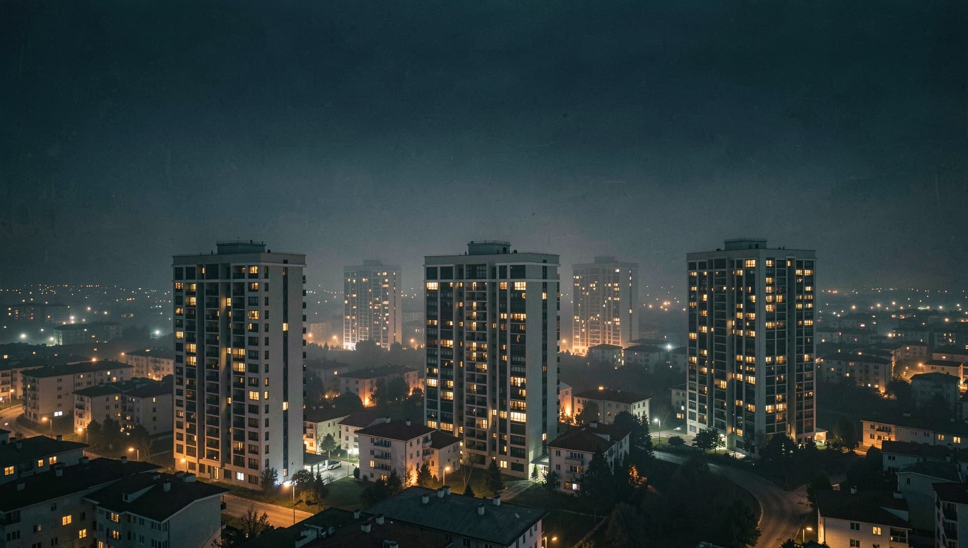 Gece sisinde ışıkları yanan birden çok konut kulesi, büyüyen bir ağ